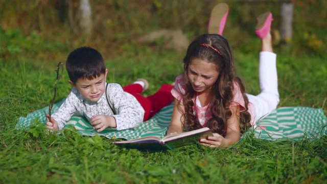 Little children reading a book in the garden.