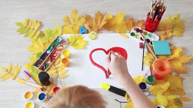 Drawing red heart on a sheet of paper. Autumn inspiration