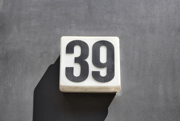 Modern, simple, monochromatic building number on concrete surface in Berlin. Strong shadow creates...