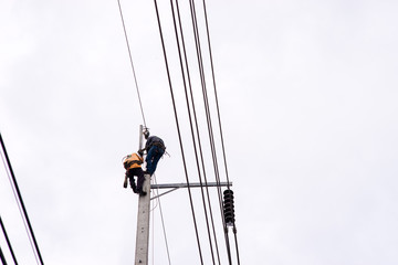 Electrician lineman repairman worker at climbing work on electric post power pole