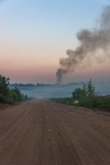 The road to the landfill of municipal solid waste. Burning garbage dump. Smoke poisons the district.
