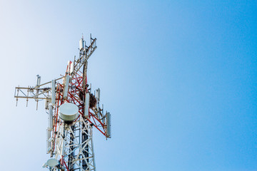 Cell phone antennas on a red and white tower