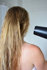 Fototapeta premium Blond woman drying hair in bathroom
