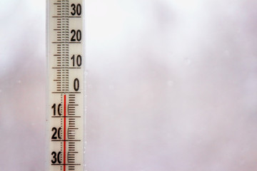 Outdoor thermometer with negative mark temperature on grey blurred background. Shallow depth of field. Focus on thermometer