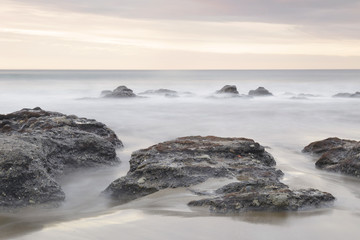 Fototapeta na wymiar Serene seascape in Azkorri beach, Biscay, Basque Country, Spain. Long exposure on a cloudy day.