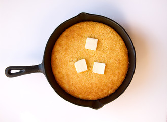 Cornbread with slices of melted butter in a cast iron skillet is
