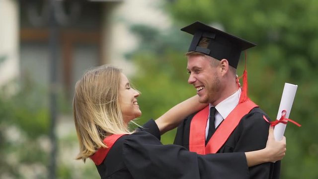 Beautiful girl hugging and kissing her boyfriend, happy graduates enjoying life
