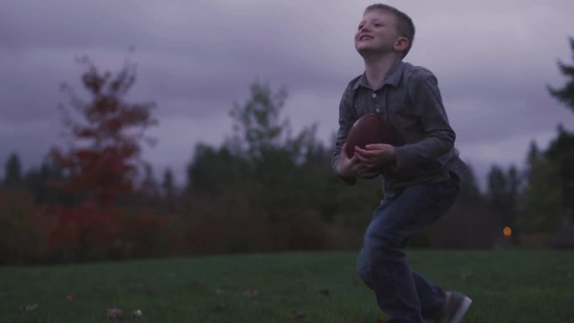 A young boy picks up a dropped a ball and throws it back