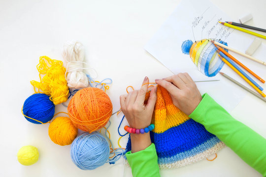 Woman knitting needles striped hat from yarn. Knitting. 