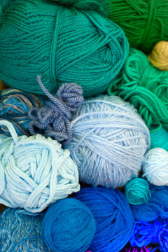 Colorful yarn stacked in a series of colors. Background brown.
