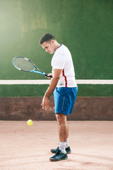 Handsome young man on tennis court. Man playing tennis. Man throwing tennis ball
