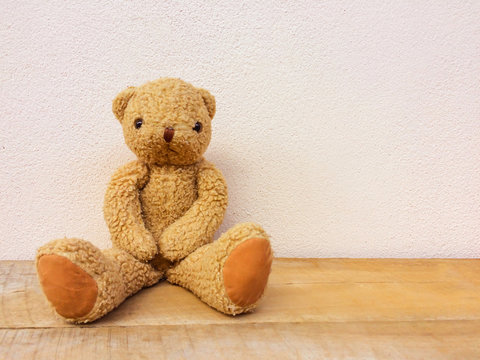 Brown teddy bear sit on the wooden floor.