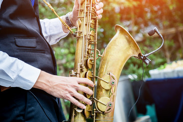 Hands of groom play on saxophone
