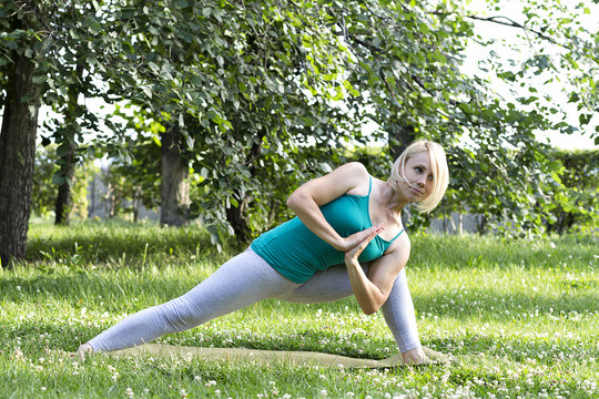  Young flexible woman doing yoga on the grass