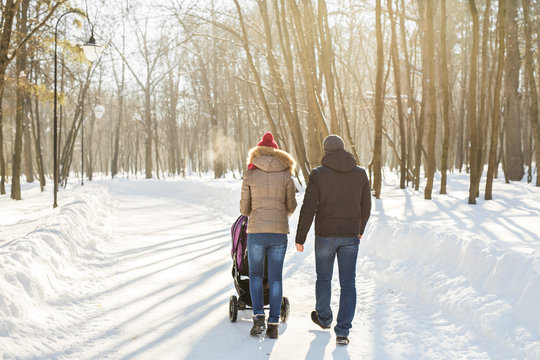 Father And Mother With Baby Carriage In Winter Forest