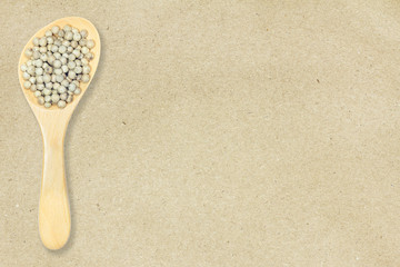 Peppercorn. White pepper in wooden spoon on recycled crumpled brown paper background for design with copy space for text or image.