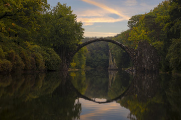 Fototapeta na wymiar Autumn over Devil's bridge in the park Kromlau, Germany 