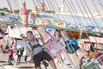 Obraz premium Couple having fun on chain carousel Ketten-Karussell at Oktoberfest