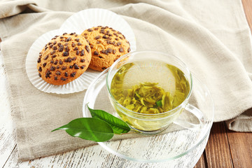 Glass cup of green tea and cookies on wooden table