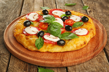 Delicious pizza with mushrooms, cherry tomatoes, olives and basil on wooden background
