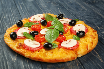 Delicious pizza with mushrooms, cherry tomatoes, olives and basil on blue wooden background