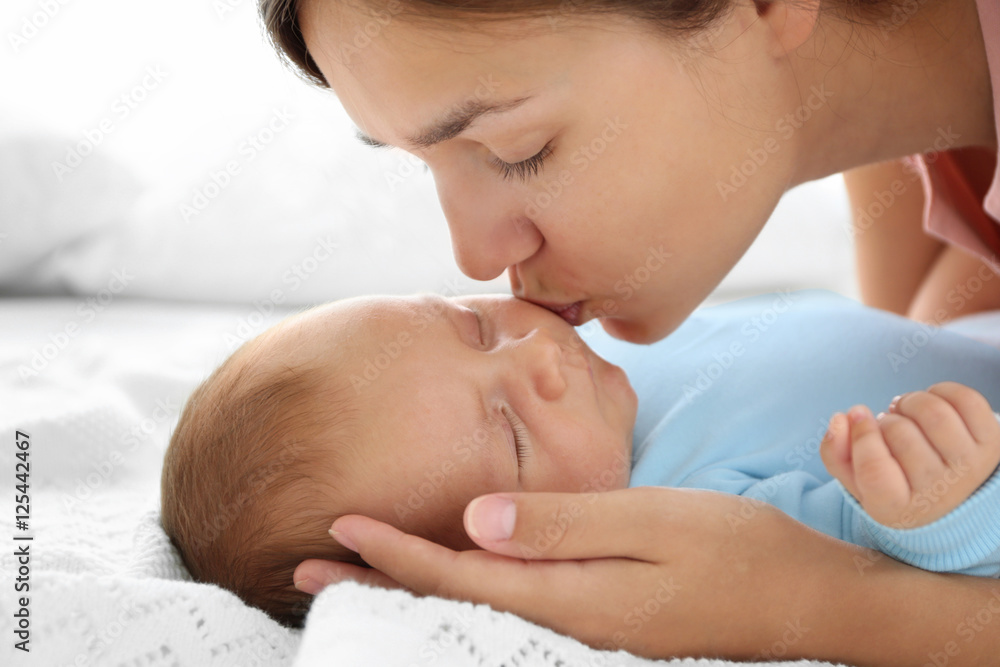 Poster Portrait of young mother kissing sleeping baby, close up view