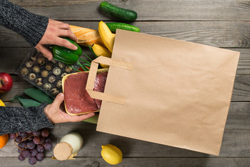 Different healthy food on wooden table with paper bag