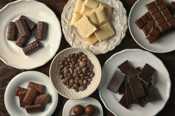Many plates with chocolate on wooden background, top view