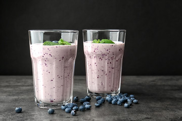 Two glasses of tasty smoothie with blueberries on grey table