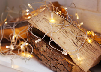 Fototapeta na wymiar Logs and lights in decorative Christmas fireplace, closeup