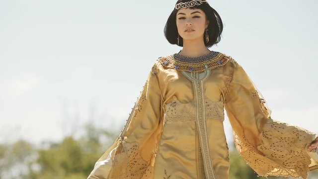 Beautiful woman like Egyptian Queen Cleopatra on in desert outdoor.