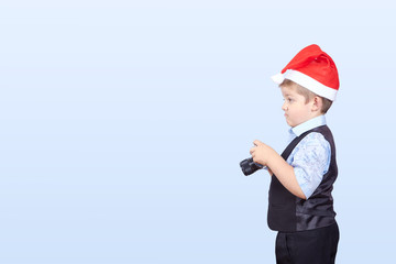 In cap of Santa Claus a little boy photographer