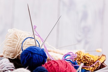 Colorful wool balls and needles in wooden basket