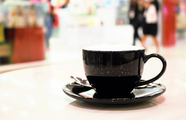 Hot coffee cup on abstract blurluxury shopping mall for background