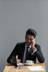 A beautiful successful man talking on phone office and writing in a notebook in cafe