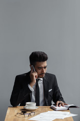 A beautiful successful man talking on phone office and writing in a notebook in cafe