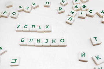 Success Is Close phrase in russian scrabble blocks. Motivational wish constructed from crossword blocks on white background