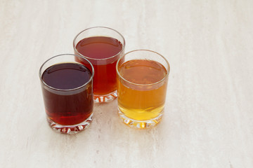 drinks of different colors and texture in glass cups on table on white background. A place for a label. Copyspace