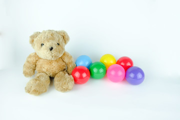 Brown bear doll with colorful balls. White background.