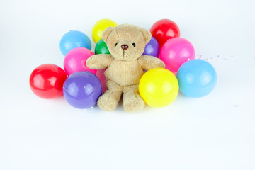 Brown bear doll with colorful balls. White background.