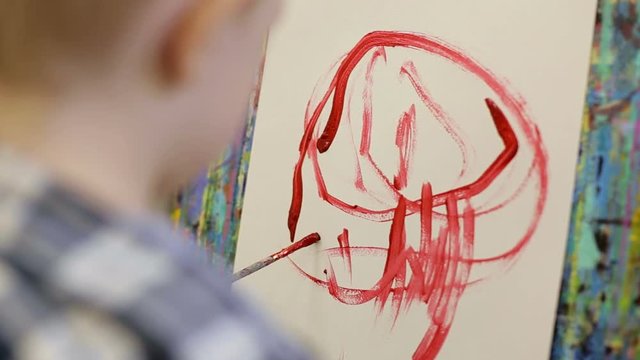 A small child draws with his left hand. The kid learns to draw.