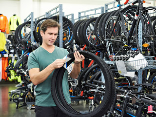 Fototapeta na wymiar Man chooses tire to bike in sports shop
