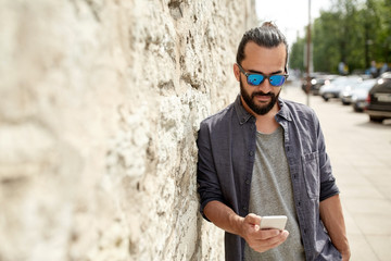 man texting message on smartphone at stone wall