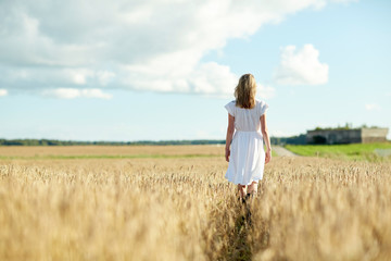 young woman in white dress walking along on field
