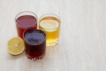 drinks of different colours and textures in glass cups on table on  light background. A place for a label. Copyspace