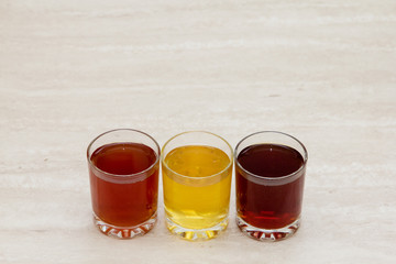 drinks of different colors and texture in glass cups on table on white background. A place for a label. Copyspace