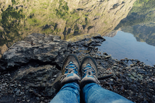 Female legs in jeans and hiking boots against mountain lake