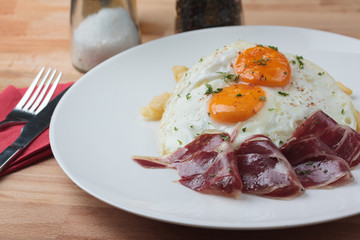 Appetizing Spanish Iberian cured ham with fried egg and chips on