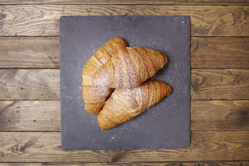 Overhead view of freshly baked croissant pastries on a wooden table top background