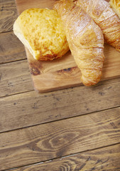 Freshly baked croissants and bread rolls arranged on a wooden background to form a page header